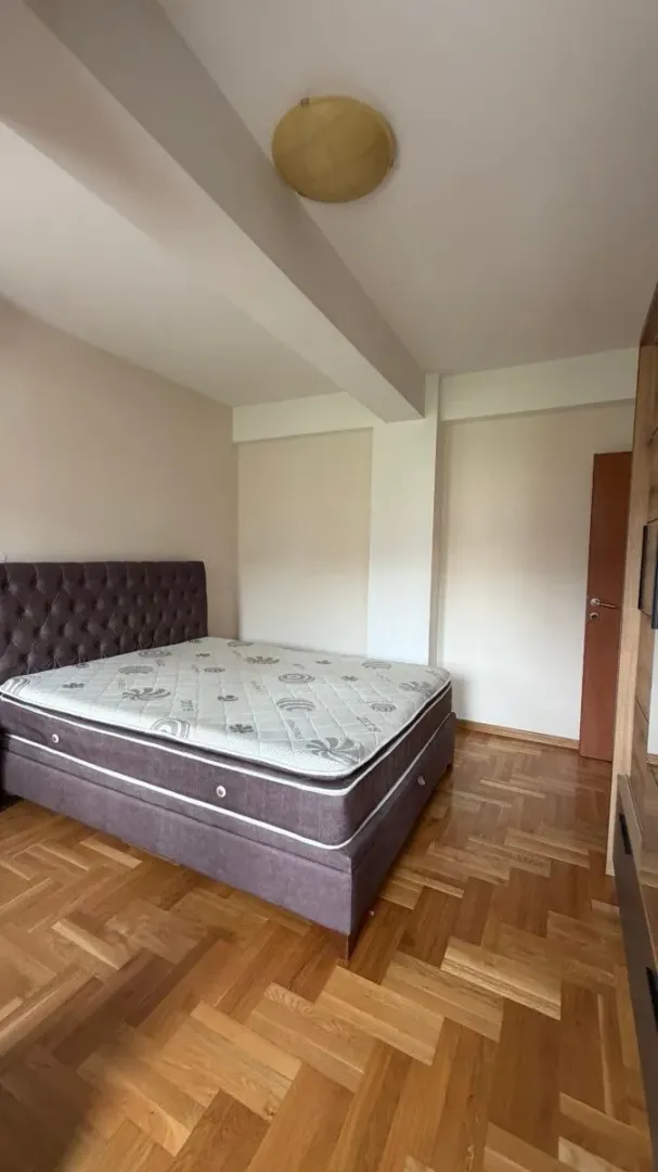 Furnished bedroom with a double bed and parquet flooring.