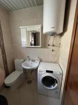 Smaller bathroom equipped with sanitary fixtures, a washbasin, a mirror, and a washing machine. - image 7