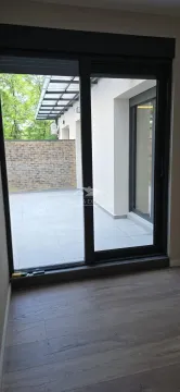 Pogled kroz balkonska vrata na popločanu terasu i dvorište. - image 11