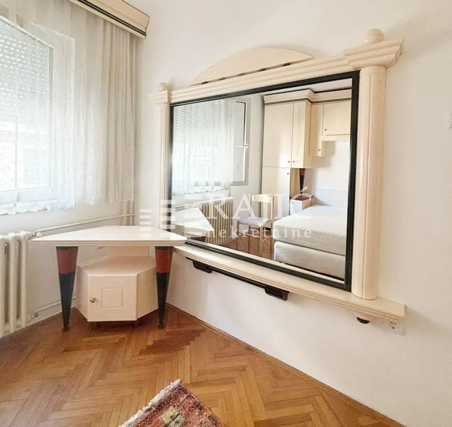 Bedroom with a large mirror and parquet flooring.
