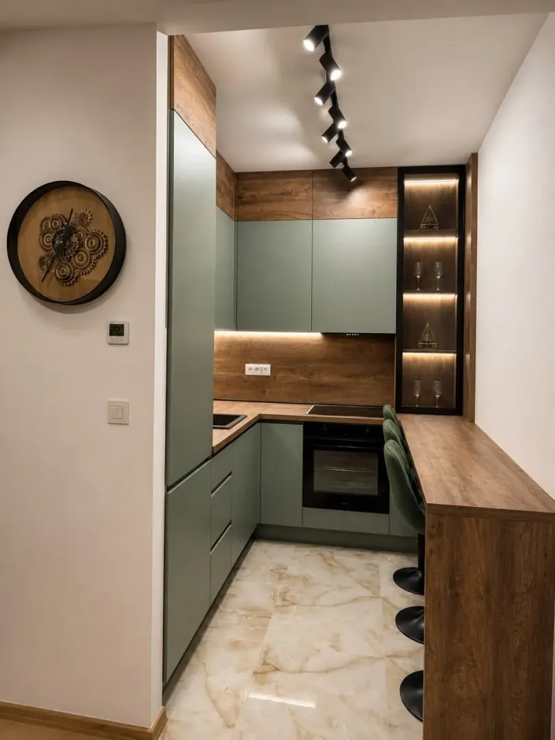 Modern kitchen with green cabinets, wooden details, and a breakfast bar.