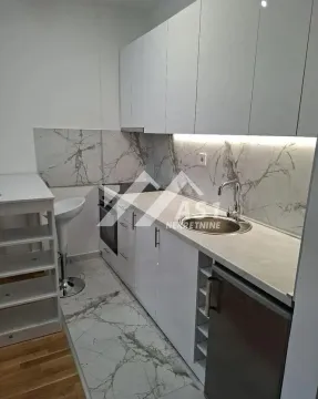 Moderna bela kuhinja sa mermernom pozadinom i ugrađenim aparatima. - image 6