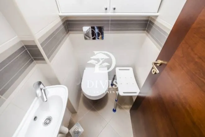Small bathroom with a toilet, washbasin, and white tiles.