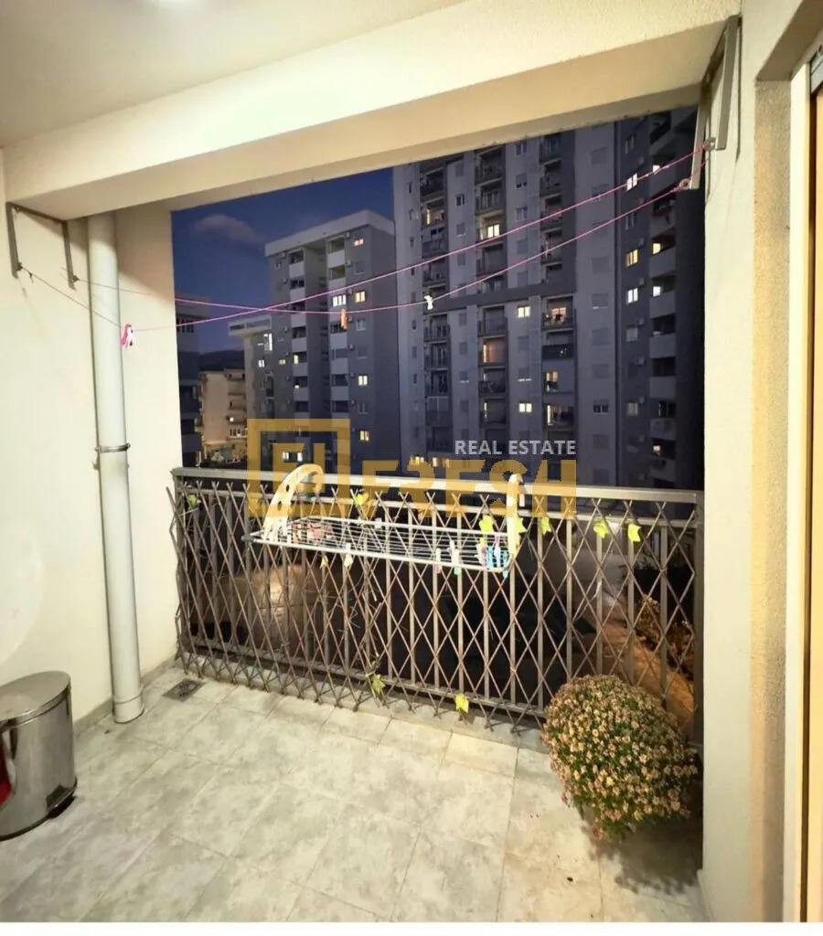 Natkriveni balkon sa metalnom ogradom i pogledom na okolne zgrade.