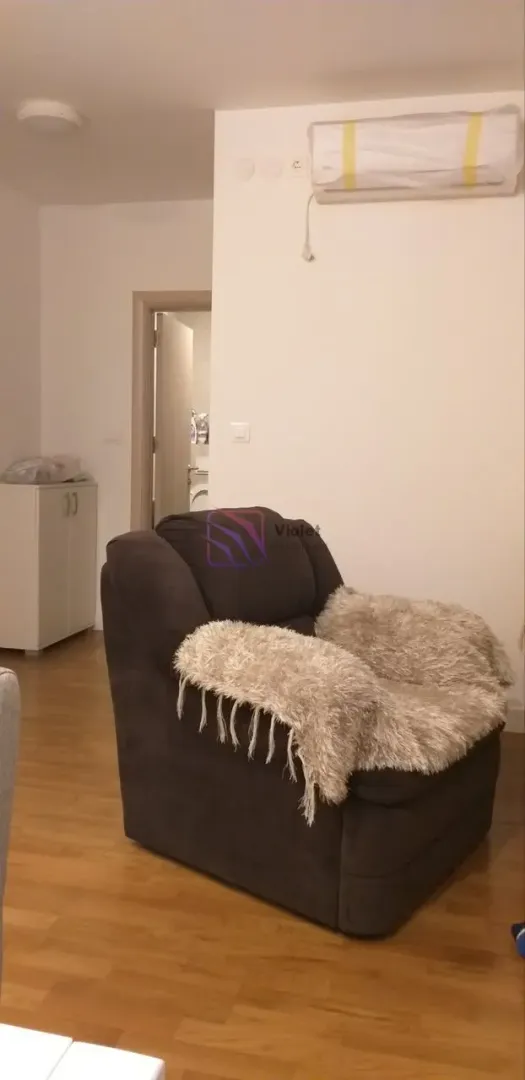 Dark armchair with a throw blanket in the living room with an air conditioner on the wall.