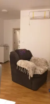 Dark armchair with a throw blanket in the living room with an air conditioner on the wall. - image 6