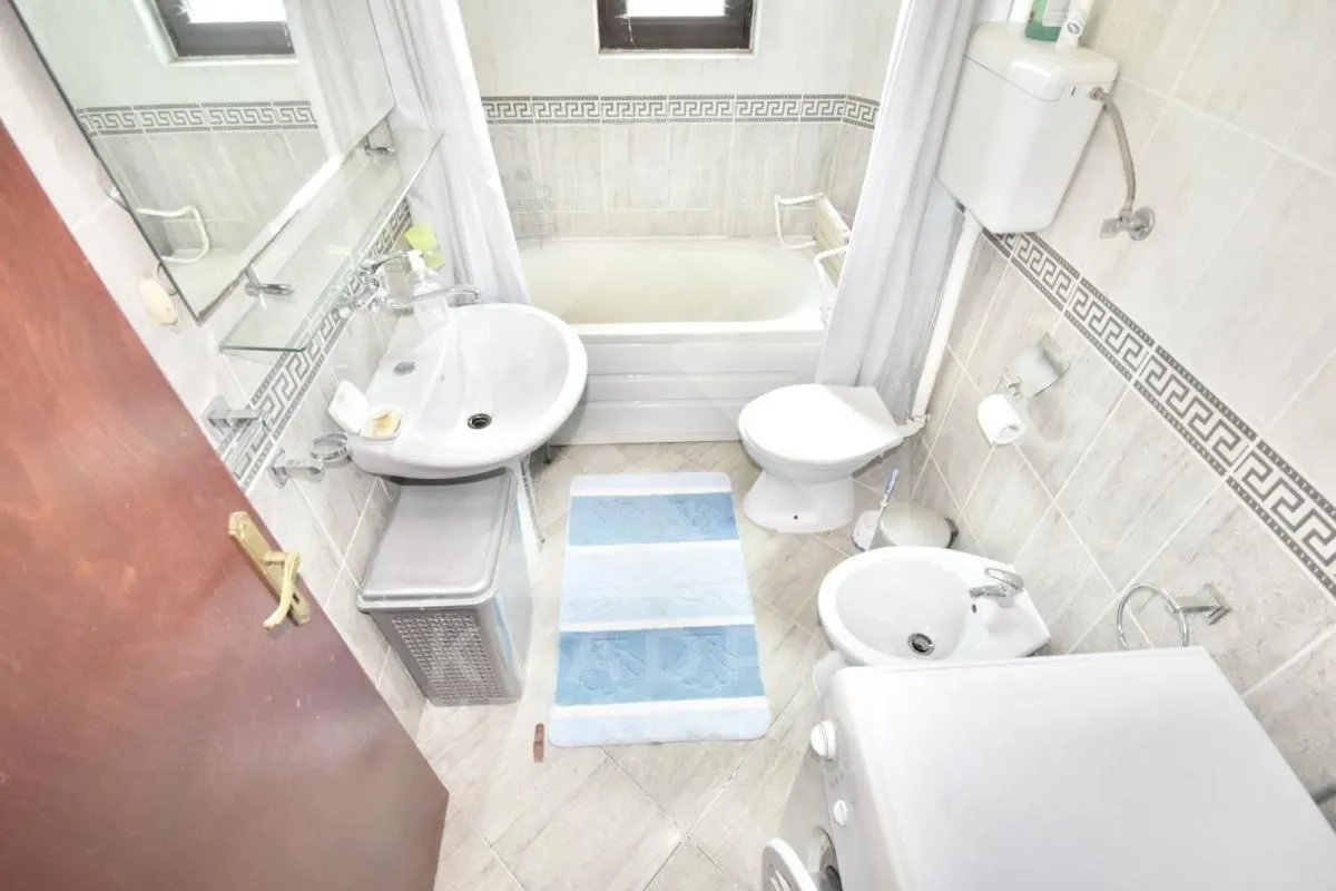 Compact bathroom with a bathtub, washbasin, toilet, bidet, and washing machine.