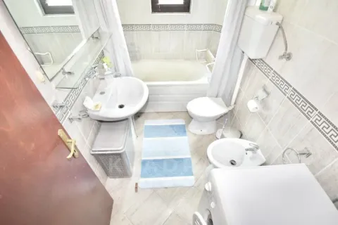 Compact bathroom with a bathtub, washbasin, toilet, bidet, and washing machine. - image 12