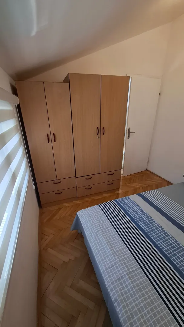 Furnished bedroom with a wardrobe and bed.