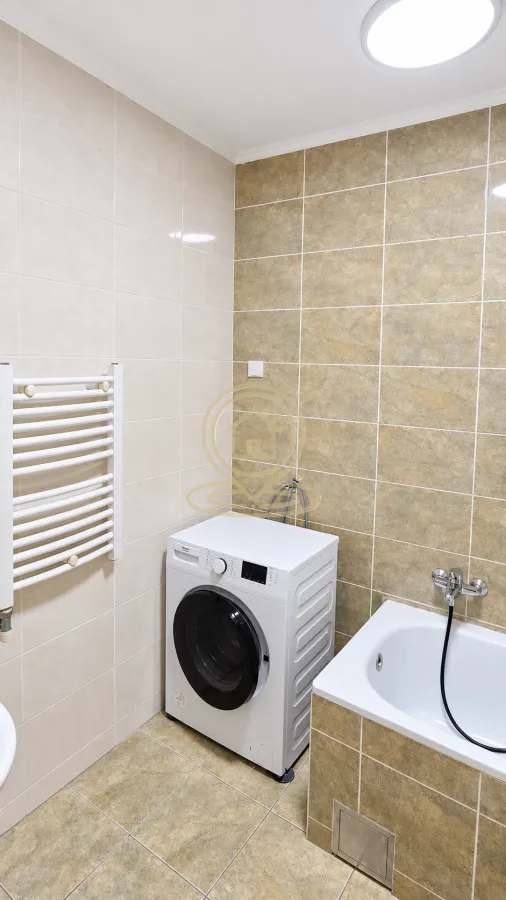Bathroom equipped with a bathtub, washing machine, and towel radiator.