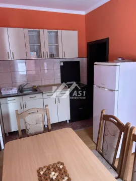Manja kuhinja sa belim elementima i trpezarijskim stolom u prvom planu. - image 2