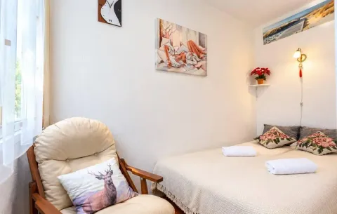 Smaller bedroom with a bed, an armchair, and wall decorations. - image 4