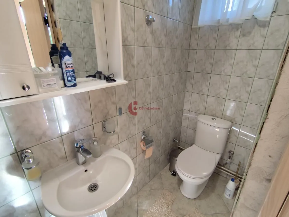 Smaller bathroom tiled with ceramic tiles, featuring a sink and a toilet.