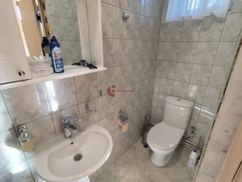 Smaller bathroom tiled with ceramic tiles, featuring a sink and a toilet. - image 31