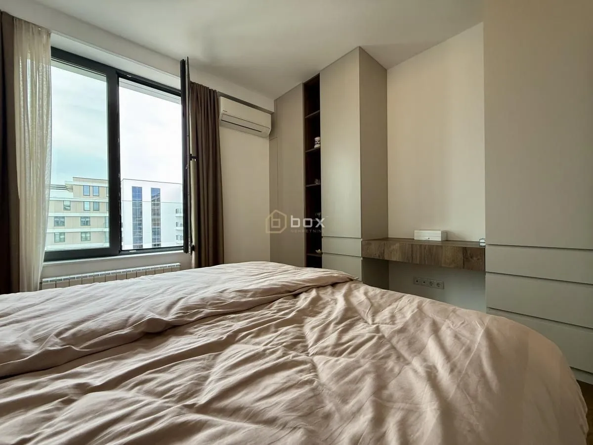 Furnished bedroom with a double bed, built-in wardrobe, and a window.