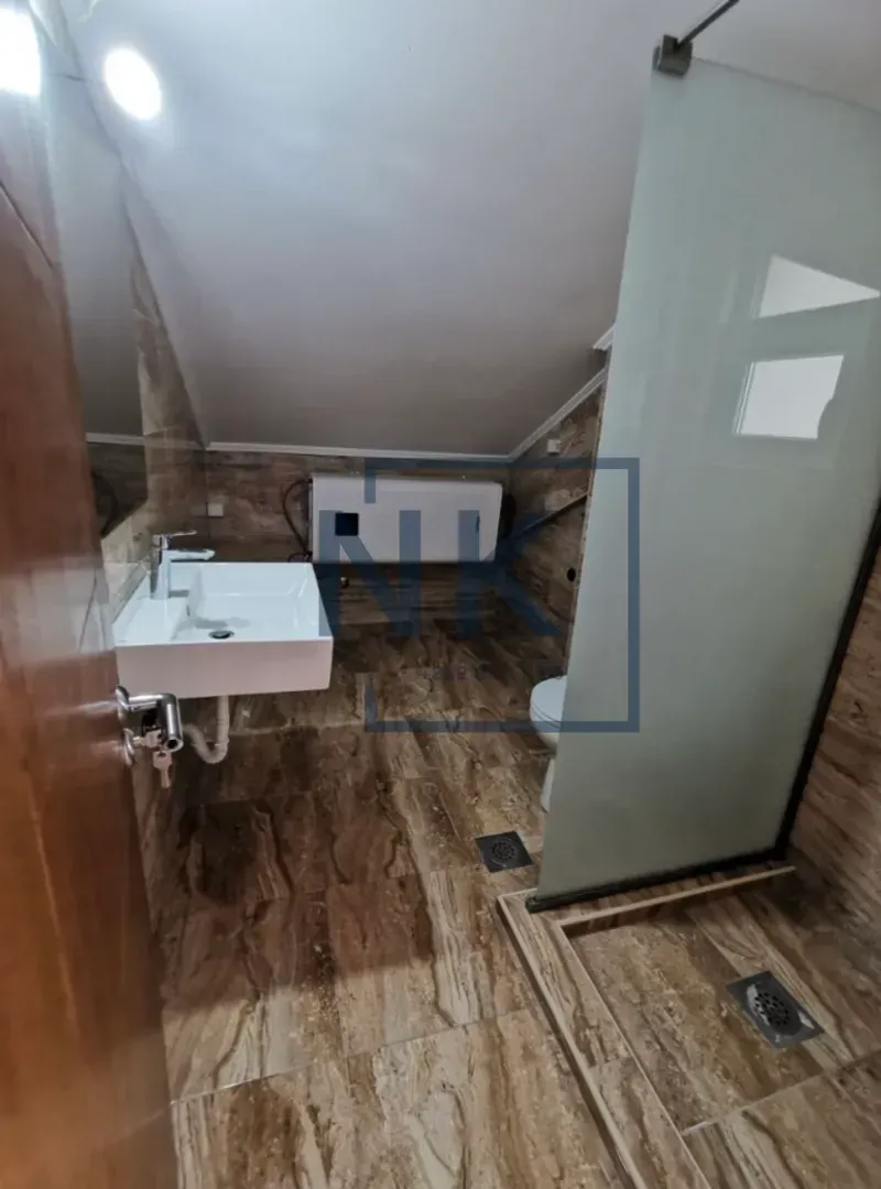 Bathroom with a washbasin, walk-in shower, and stone-effect tiles.