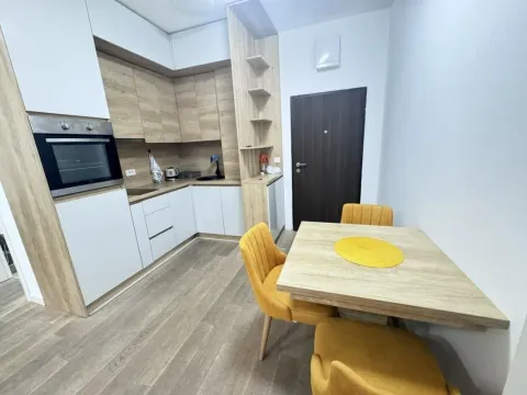 Kuhinja opremljena bijelim i drvenim elementima sa ugradnom rernom i trpezarijskim stolom sa žutim stolicama. - image 7