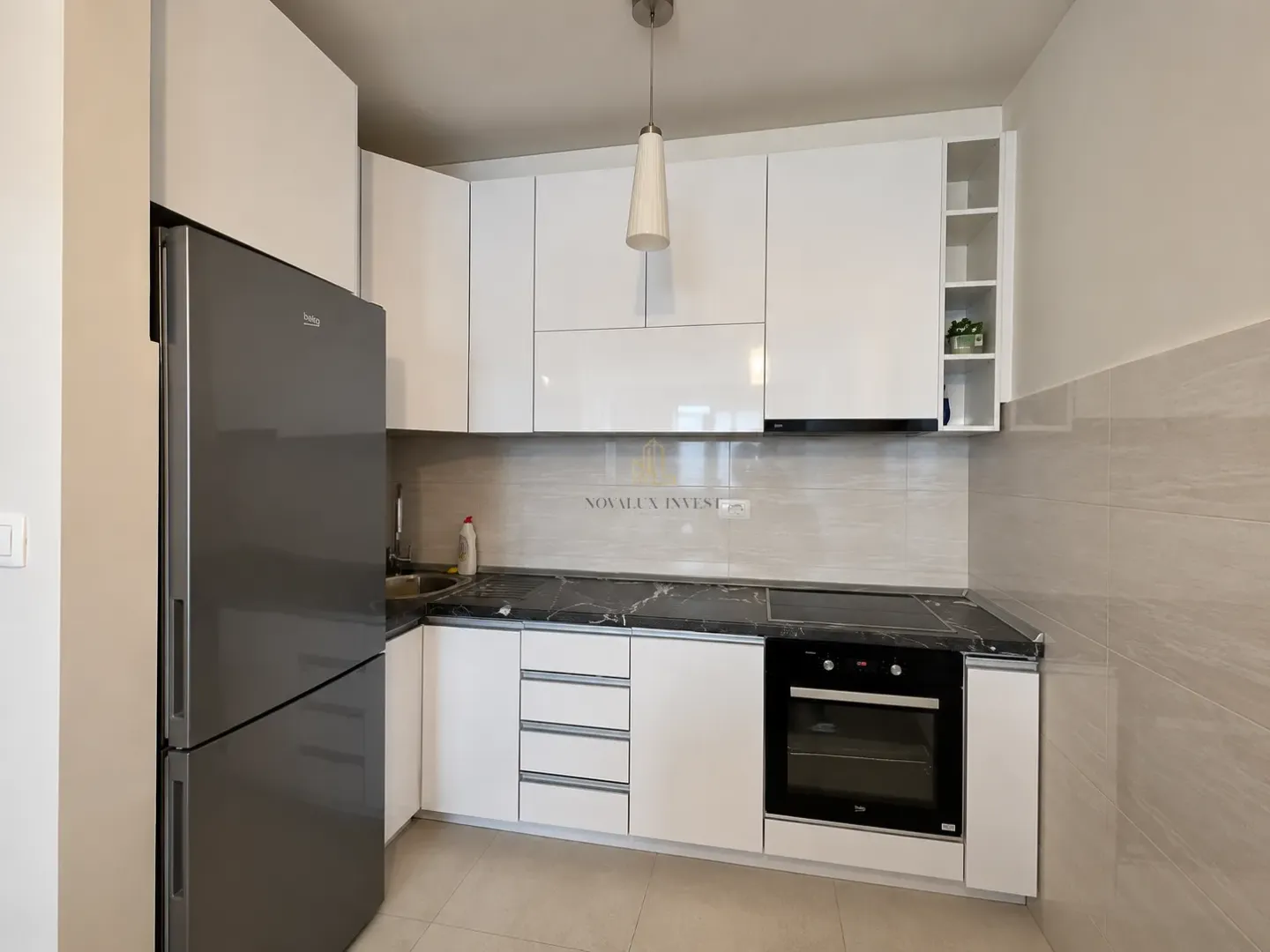 White kitchen with black countertops, built-in appliances, and a large refrigerator.