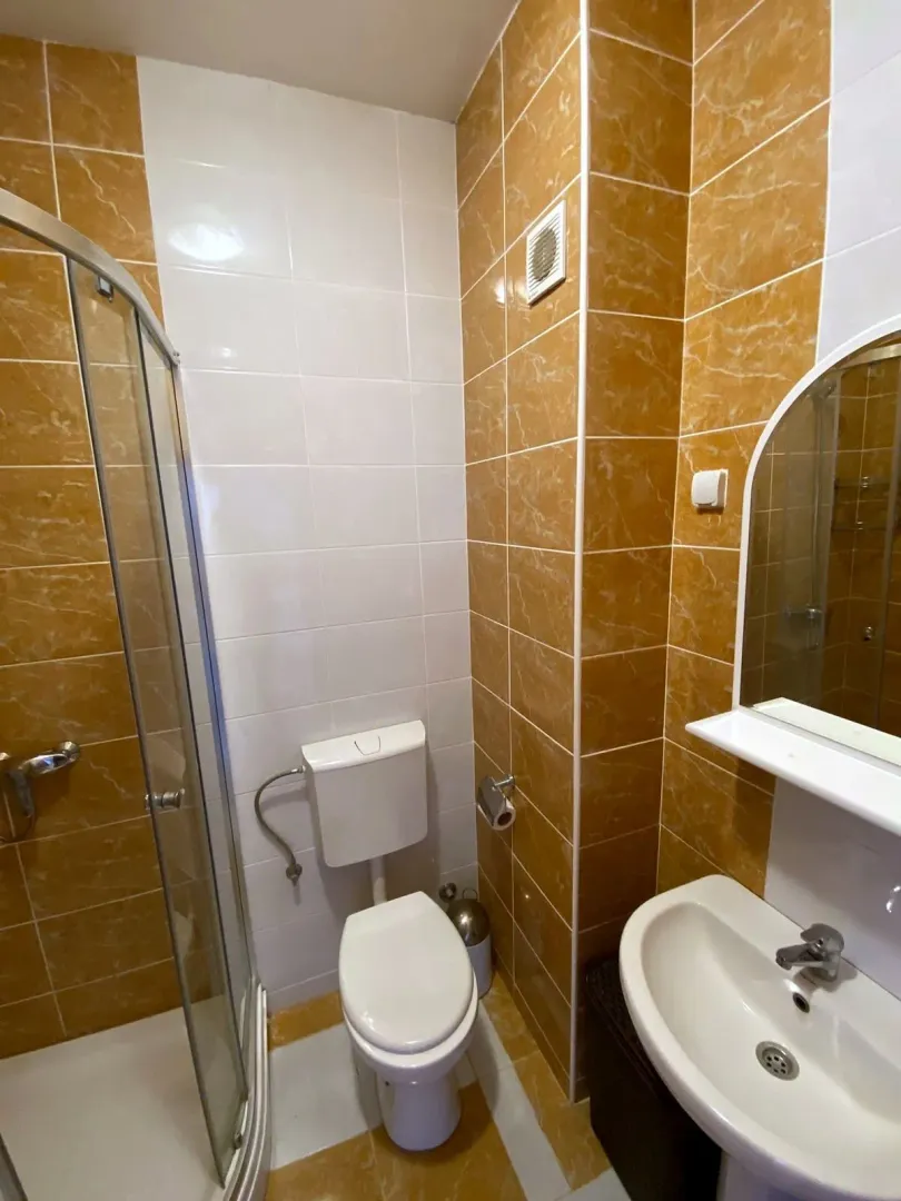 Kupatilo sa tuš kabinom, umivaonikom i toaletom obloženo keramičkim pločicama.