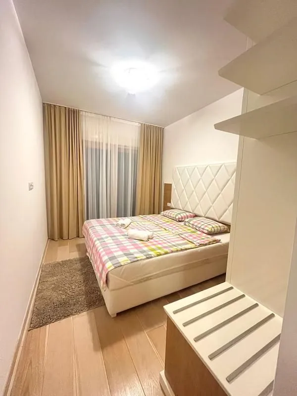 Spavaća soba sa bračnim krevetom i prozorom sa zavjesama.