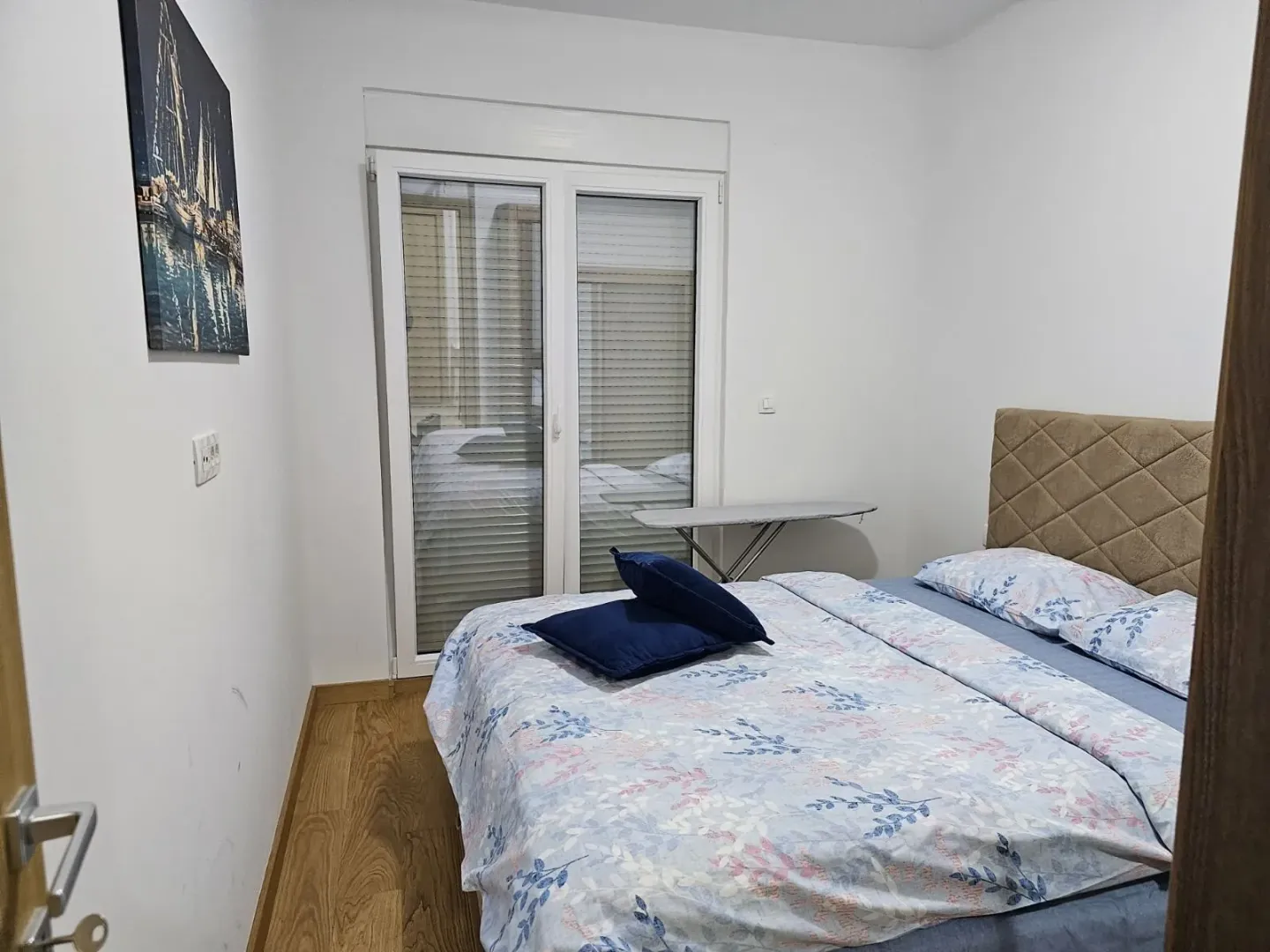 A bright bedroom with a double bed and balcony doors.