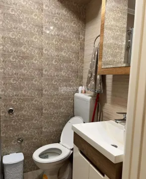 Smaller bathroom with a toilet, washbasin, and mirror. - image 12