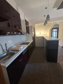 Moderna kuhinja sa tamnim elementima i šankom. - image 3