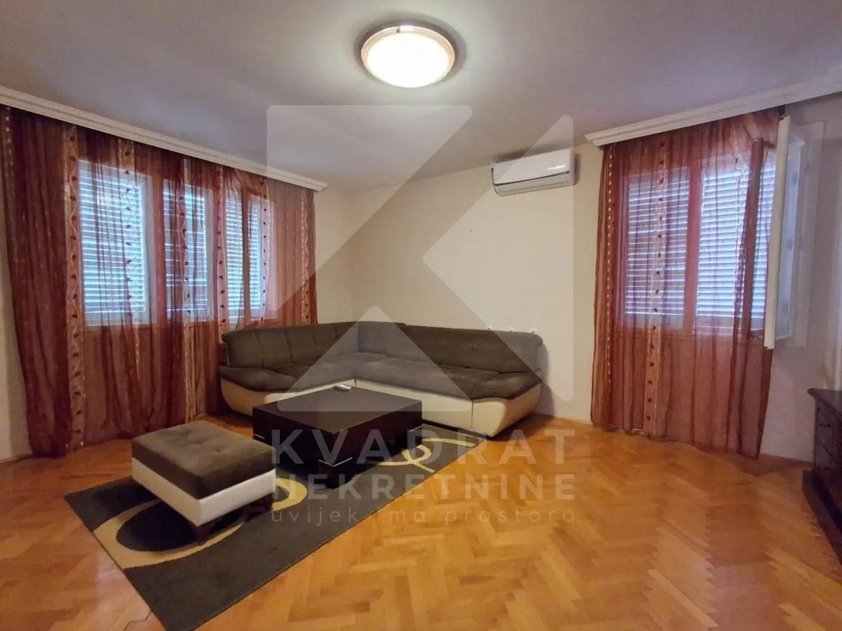 Living room with a sofa, coffee table, and windows with curtains.