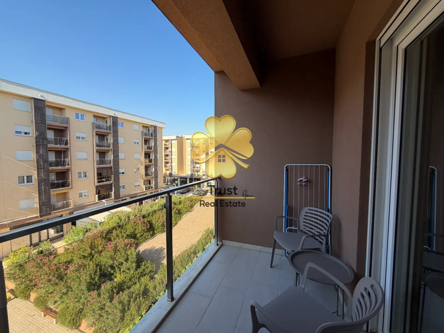 Furnished balcony with seating set and neighborhood view.