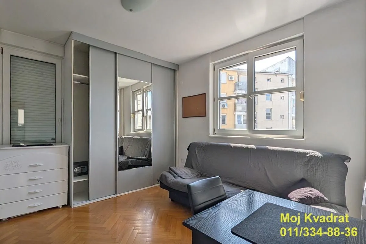 Living room with a sofa, large wardrobe, and a window.