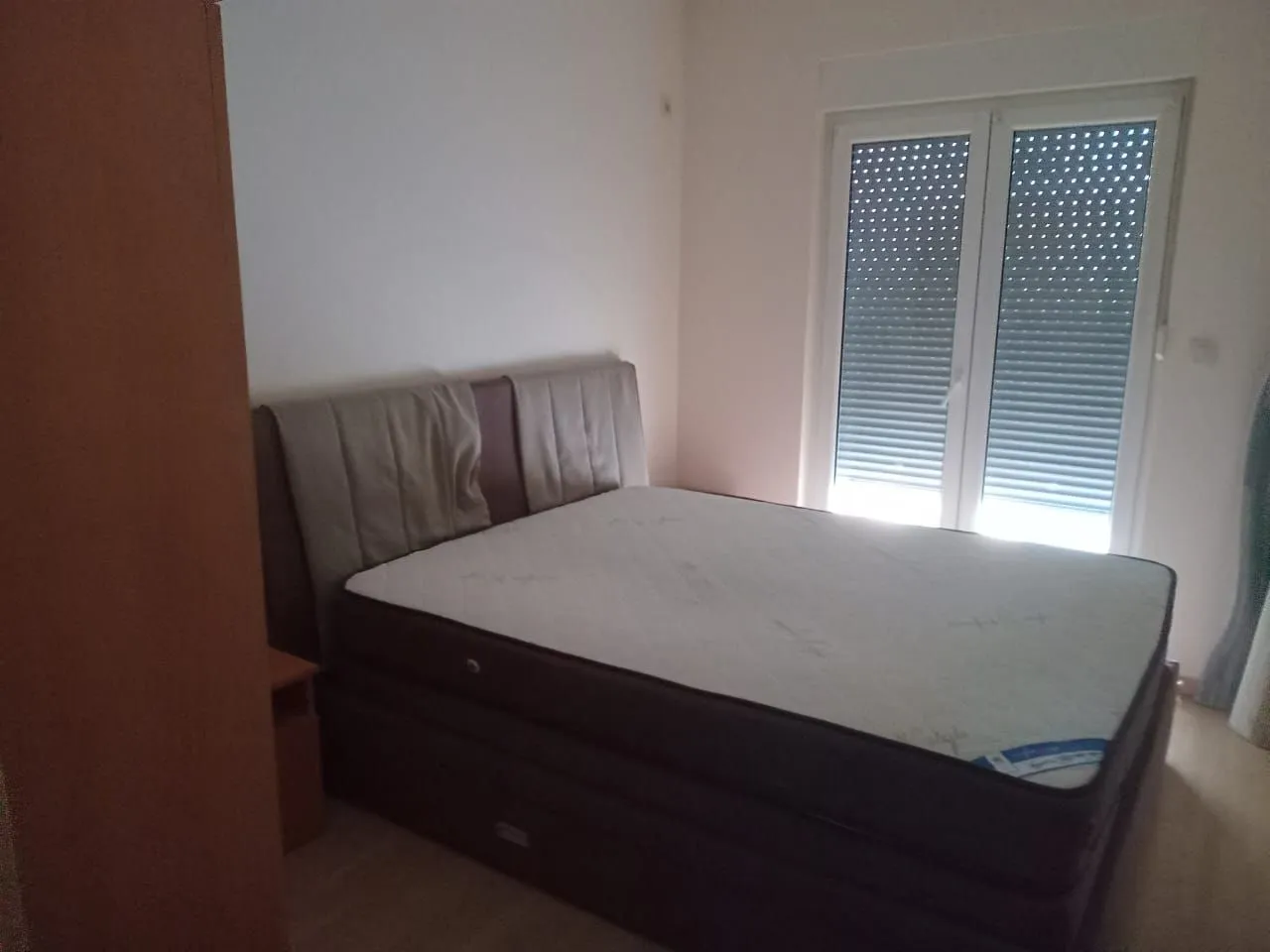 Spavaća soba sa bračnim krevetom i balkonskim vratima.