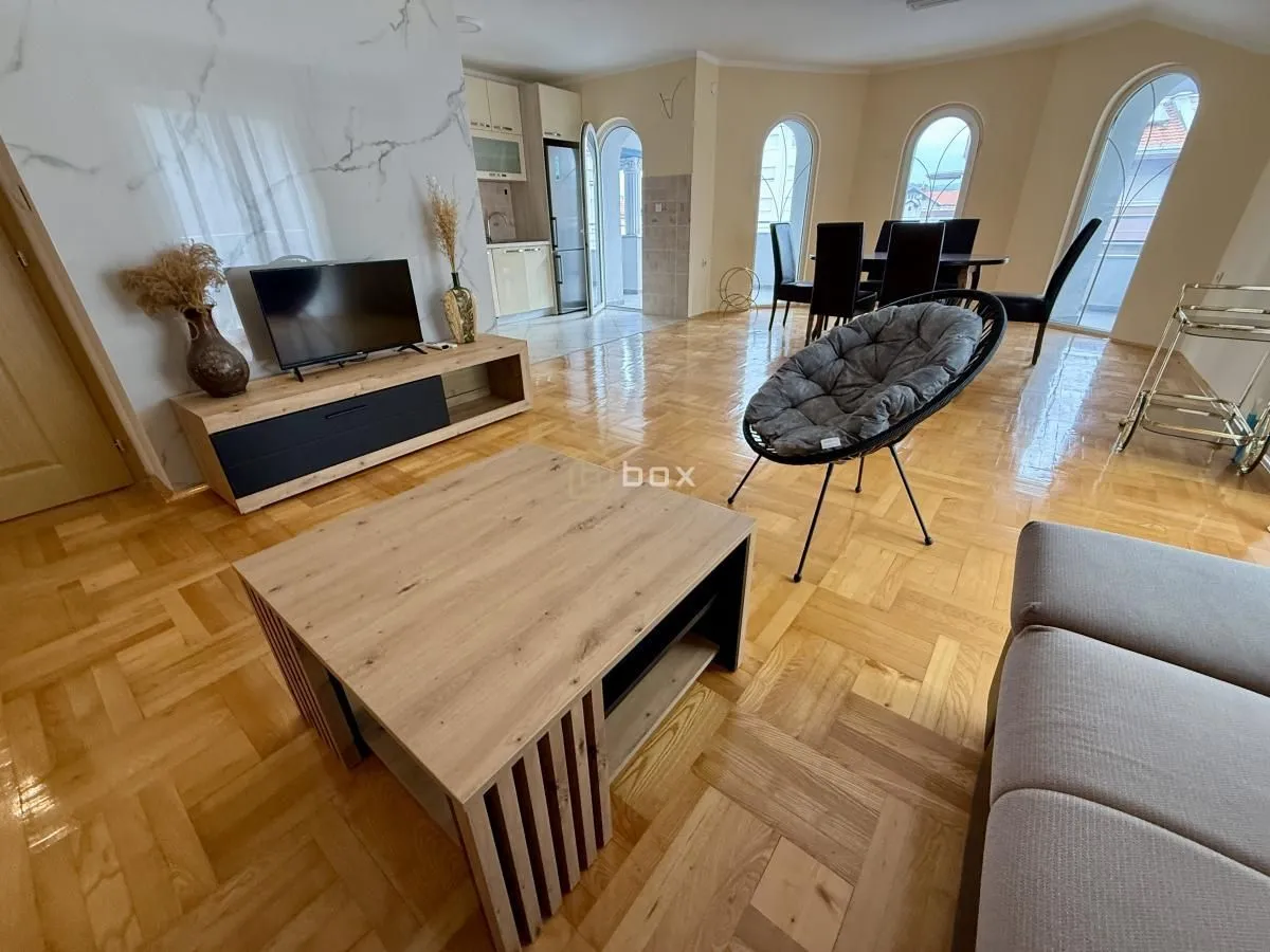 Spacious living room with seating area, dining space, and kitchen in the background.