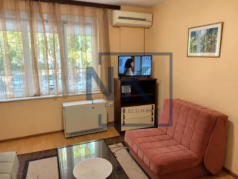 Living room with a sofa, TV, and window with curtains.