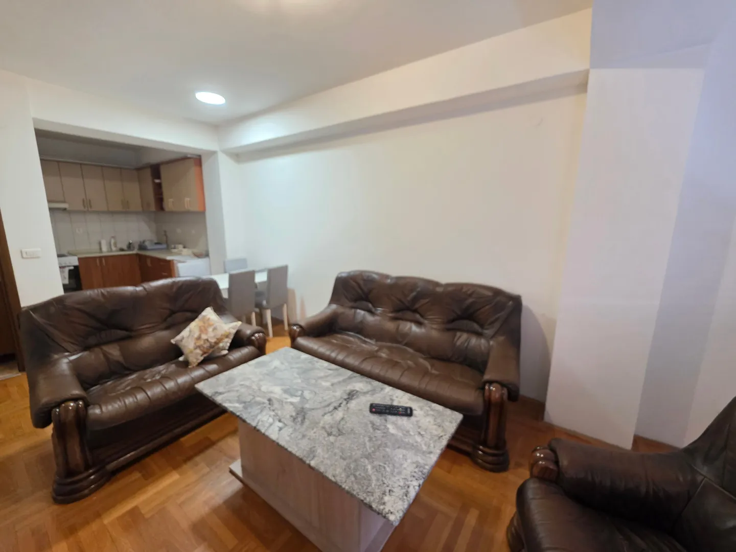 Spacious living room with sofa set and table, connected to the dining area and kitchen.