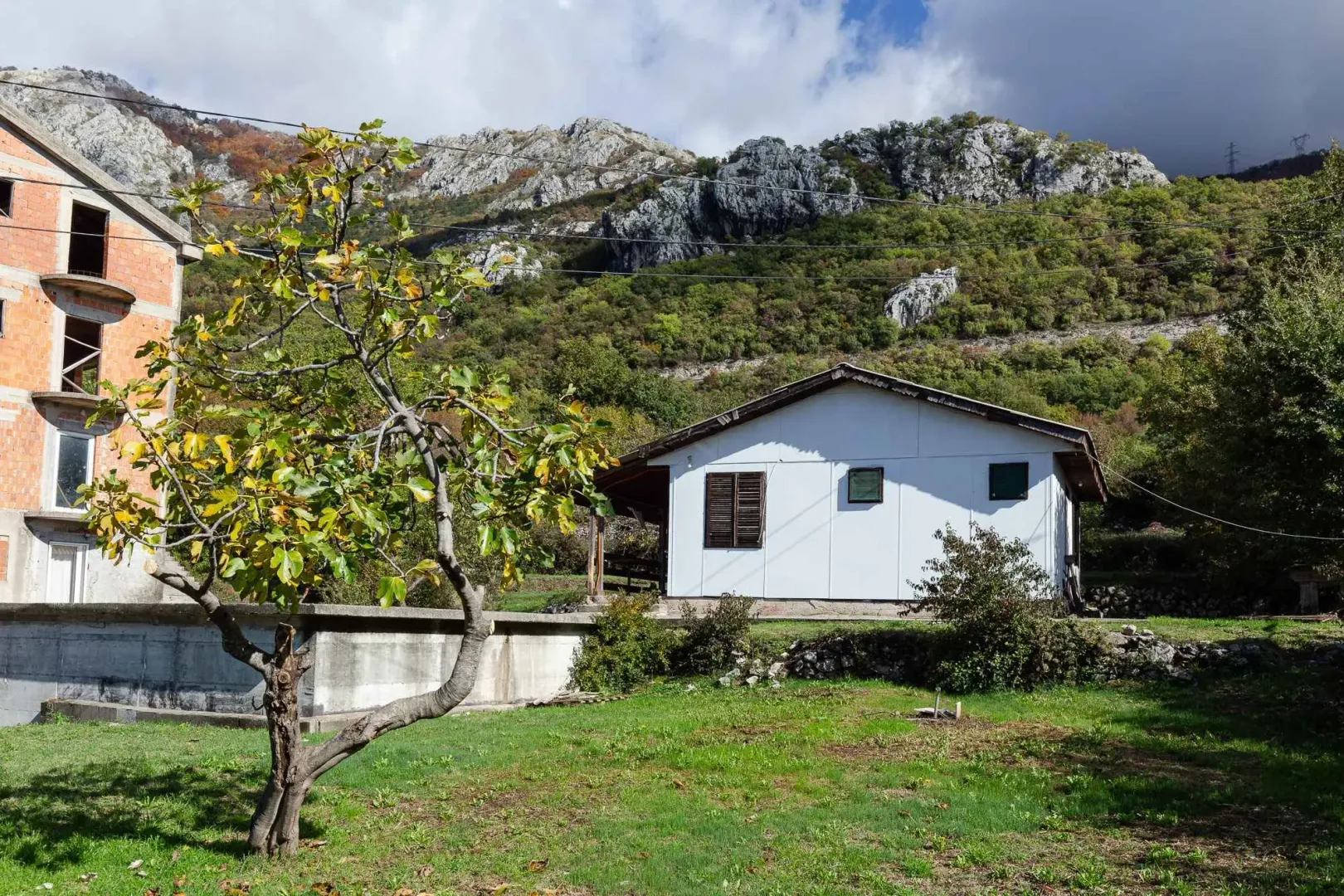 Pogled na dvorište i kuću sa planinskim pejzažem u pozadini.