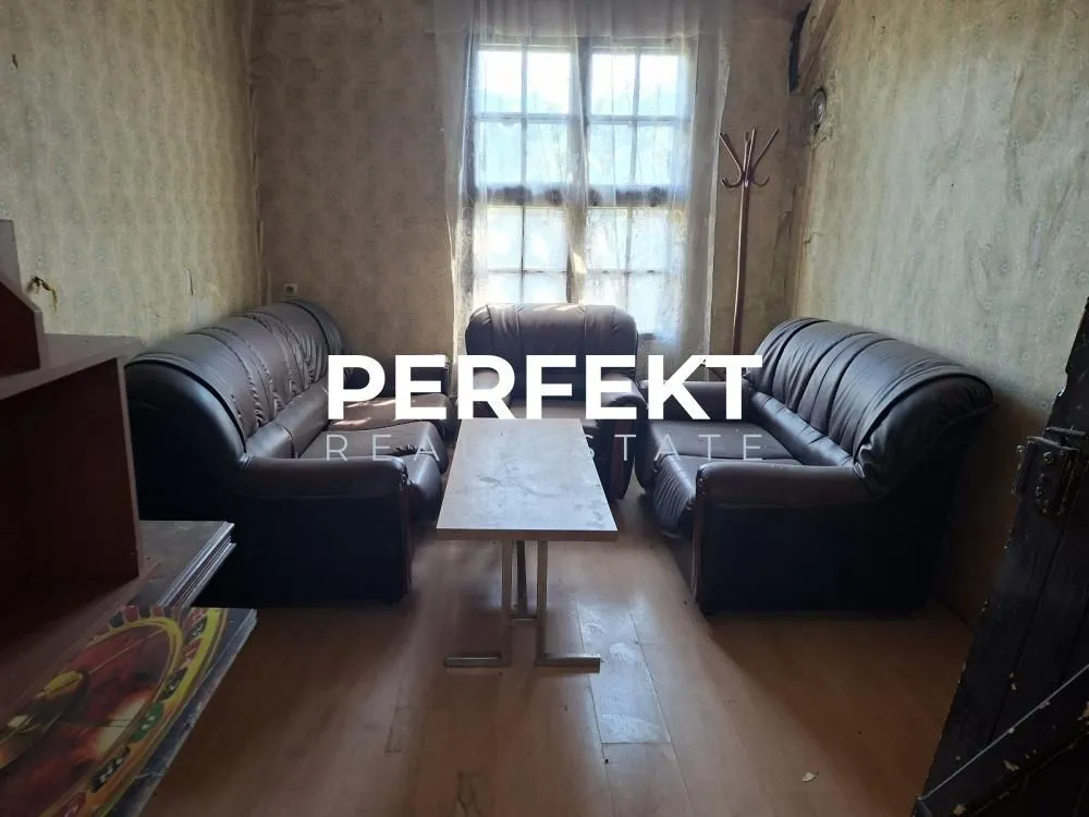 Manja dnevna soba sa garniturom za sedenje i prozorom.