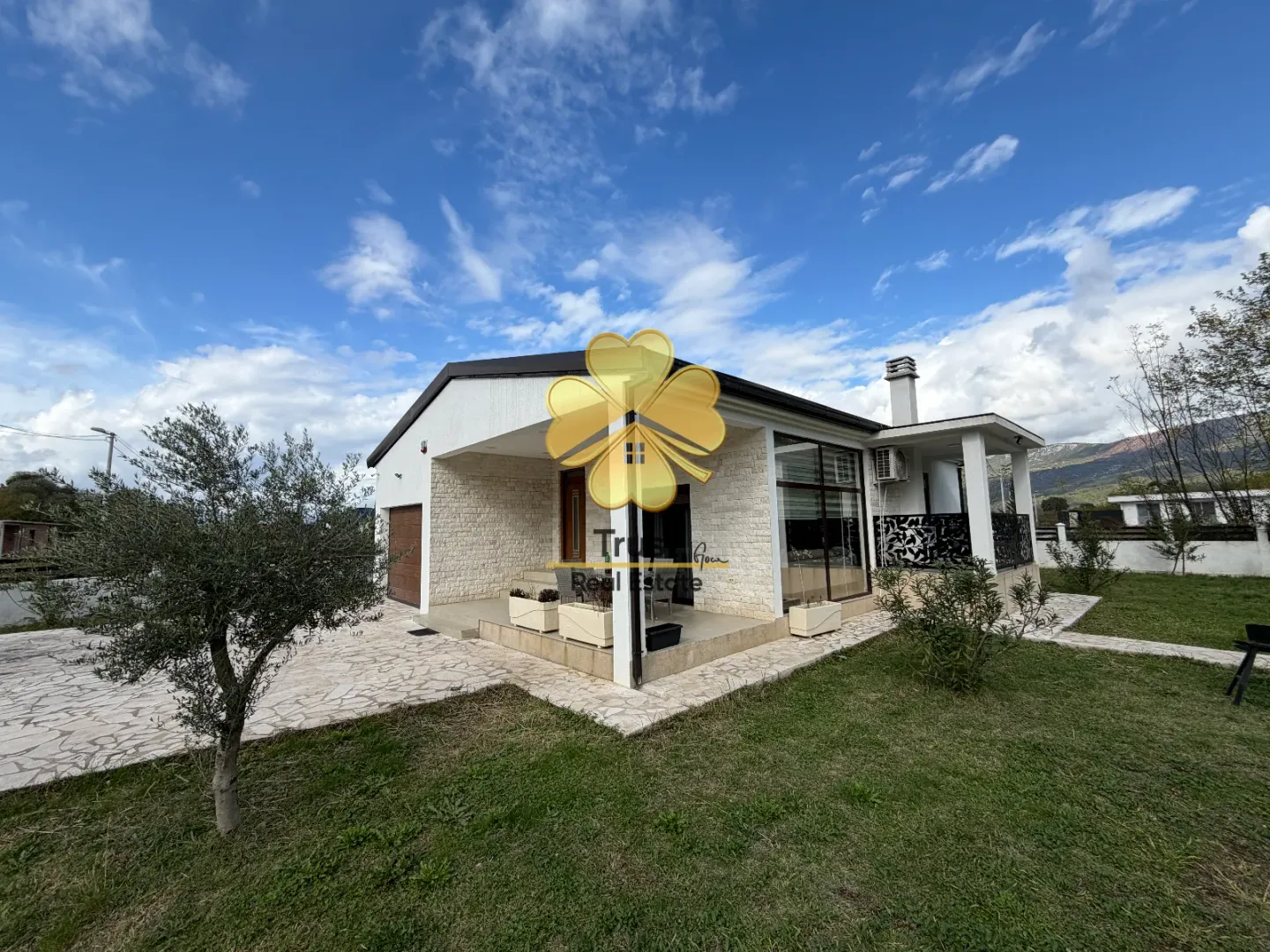 Exterior of a ground-floor house with a yard and paved driveway.