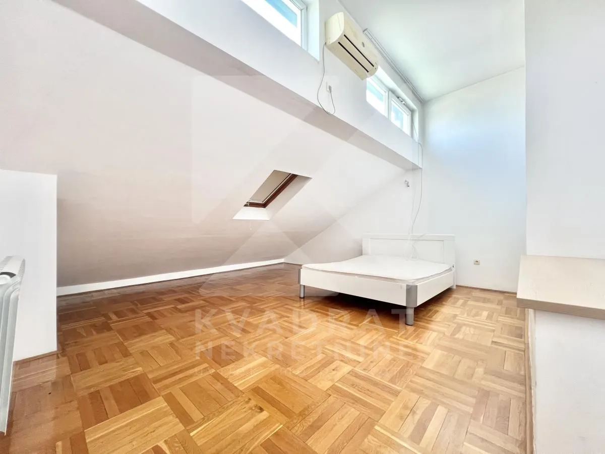 Attic bedroom with parquet flooring and a bed.