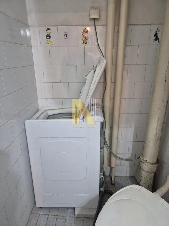 Kupatilo sa mašinom za veš i belim zidnim pločicama sa nalepnicama.