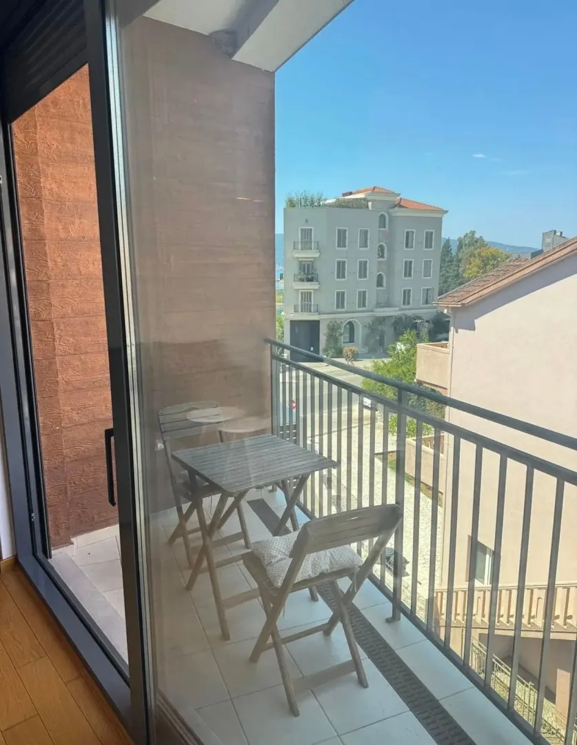 Manji namješten balkon sa garniturom za sjedenje i pogledom na okolne zgrade.