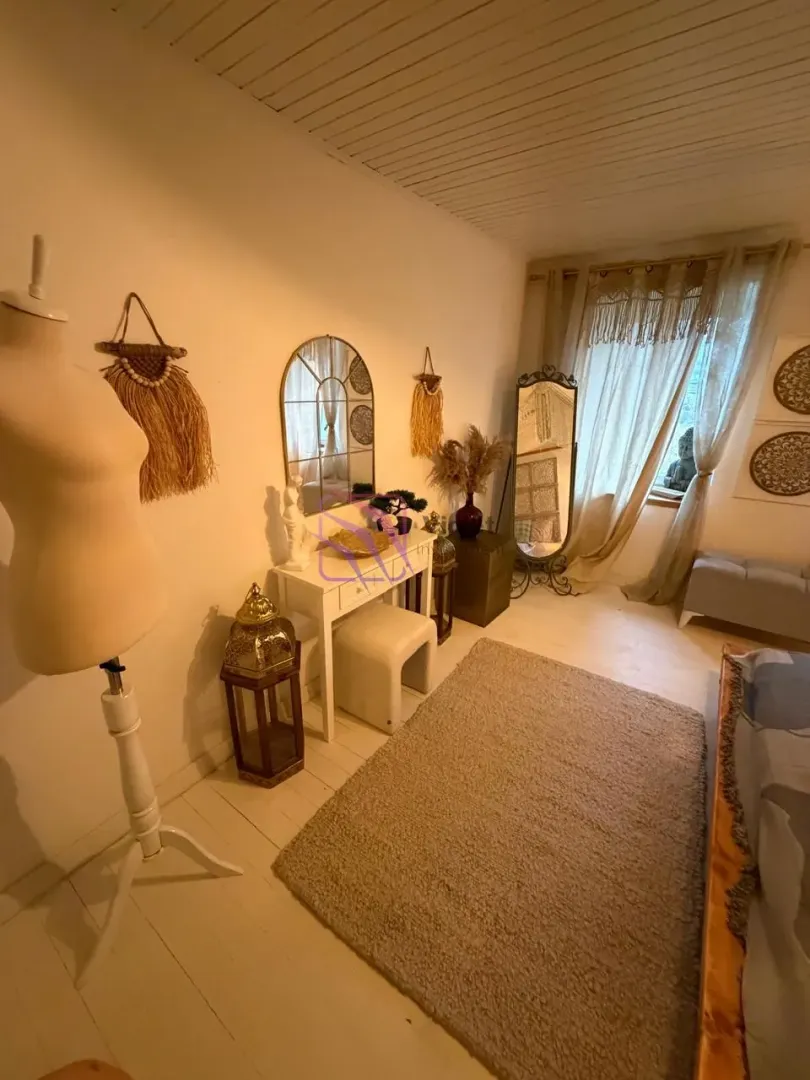 Bedroom with a bed, white furniture piece, and decorative elements.