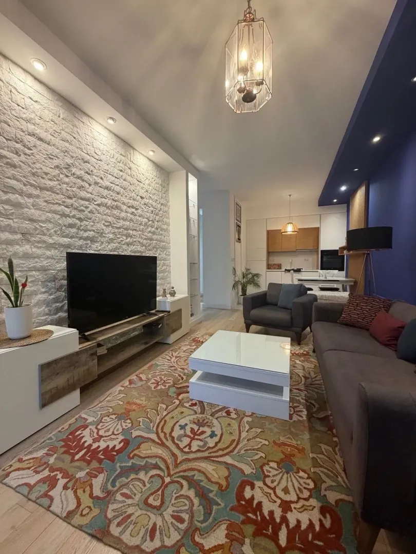 Modern living room with a sofa, TV, and decorative brick wall.