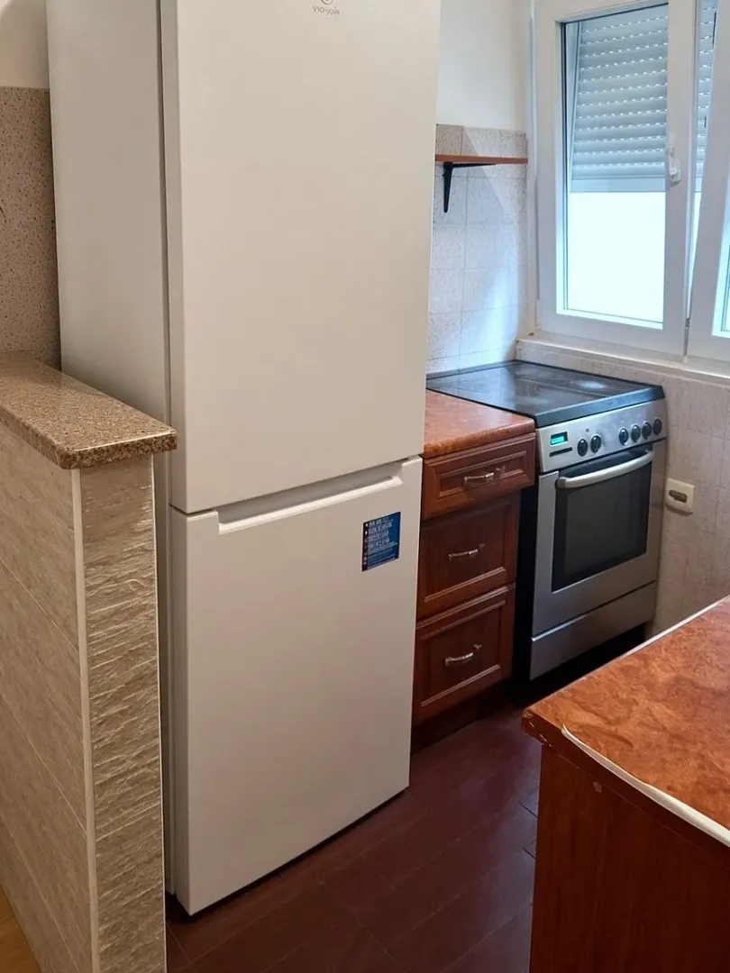 Compact kitchen with a white refrigerator, stove, and wooden cabinetry.
