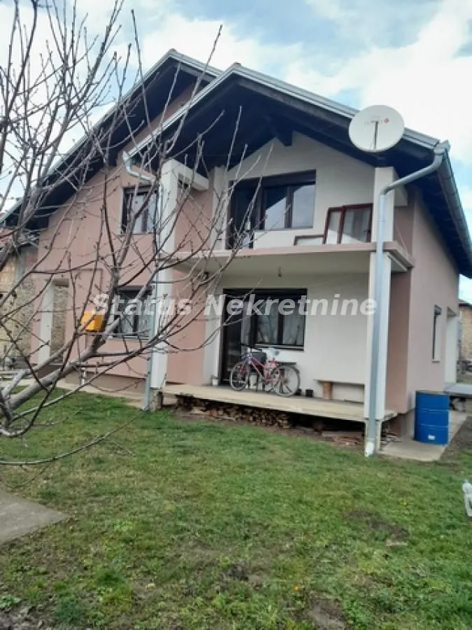 Pogled na dvospratnu kuću sa dvorištem i terasom.