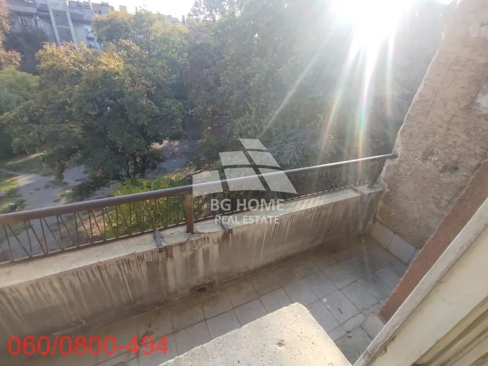 Balkon sa pogledom na zelene površine i drveće.