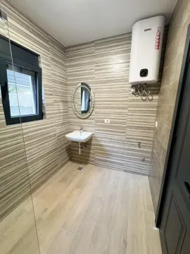 Kupatilo obloženo keramičkim pločicama sa umivaonikom i bojlerom na zidu. - image 11