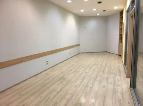 An empty, bright room with light laminate flooring and recessed ceiling lights. - image 8