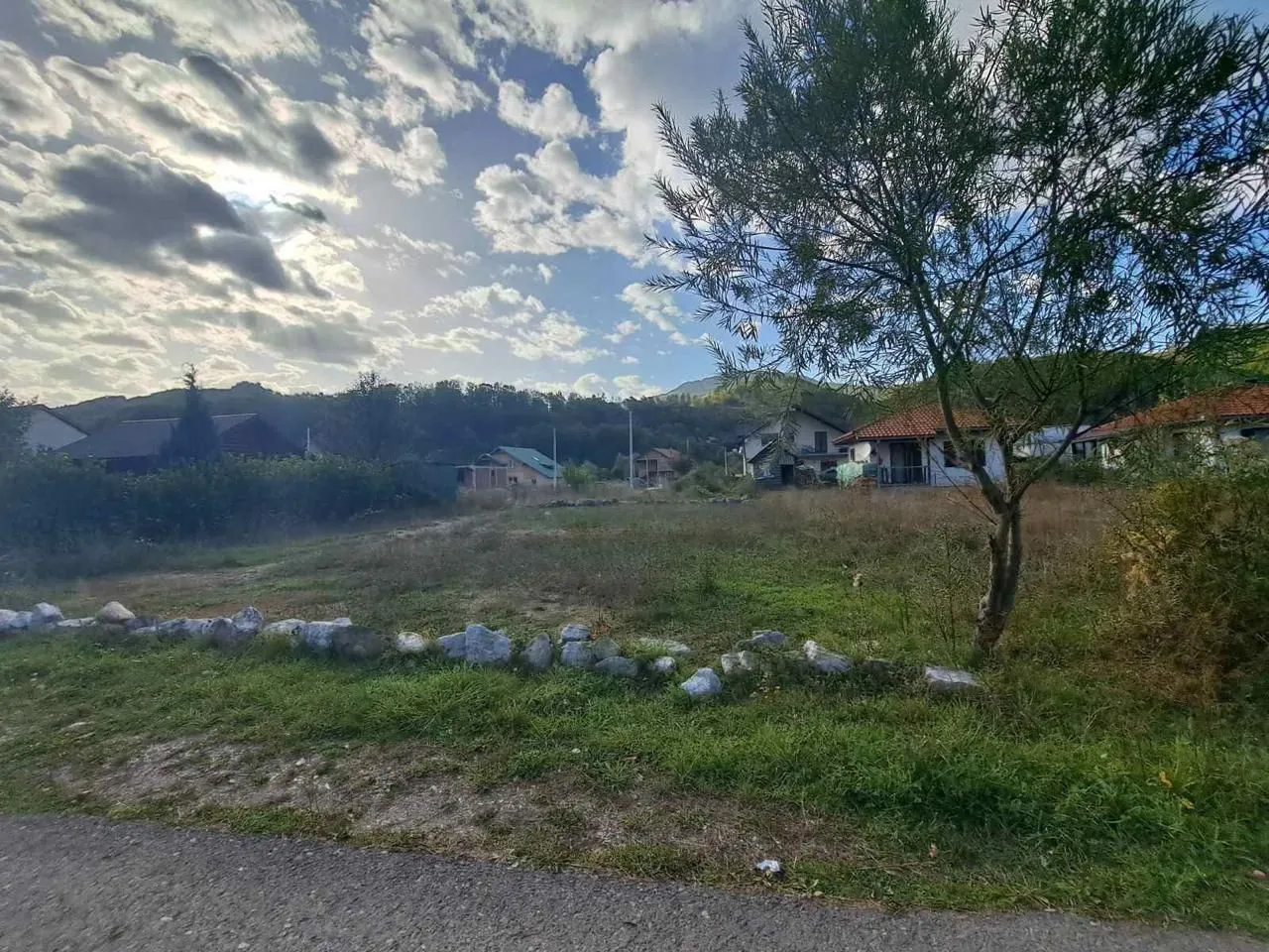 Pogled na prostrani plac sa kućama u pozadini.