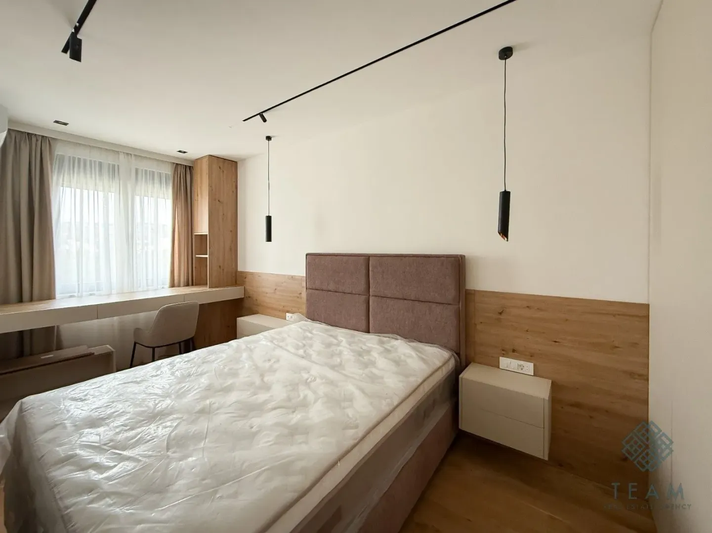 Modern bedroom with a double bed, wooden wall paneling, and a desk.
