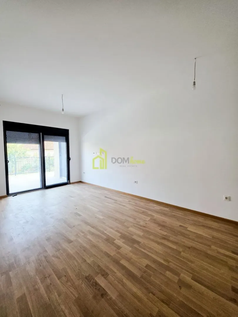 Empty room with wooden flooring and access to the terrace.